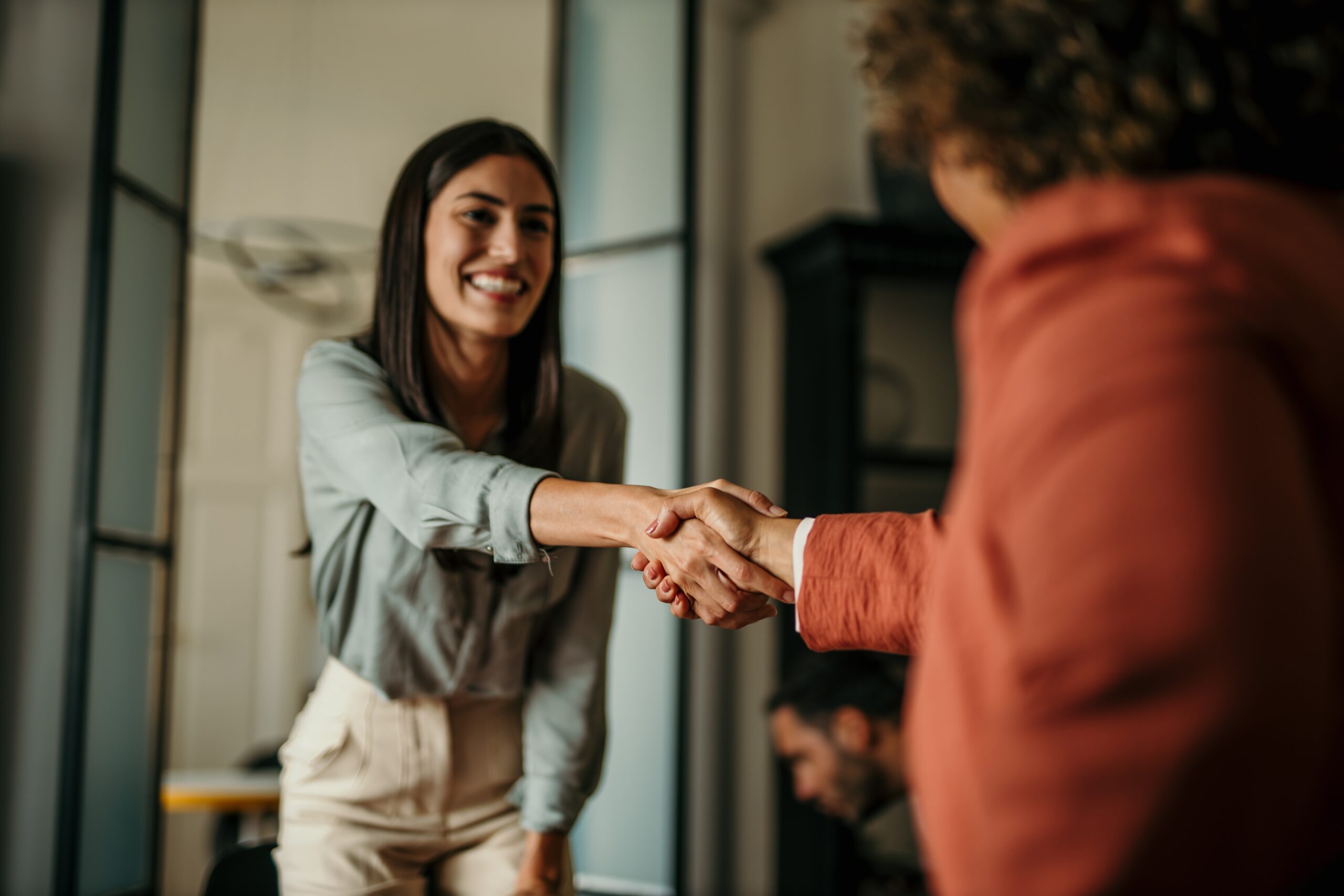 A female applicant aced an interview, shaking hands with a recruiter.