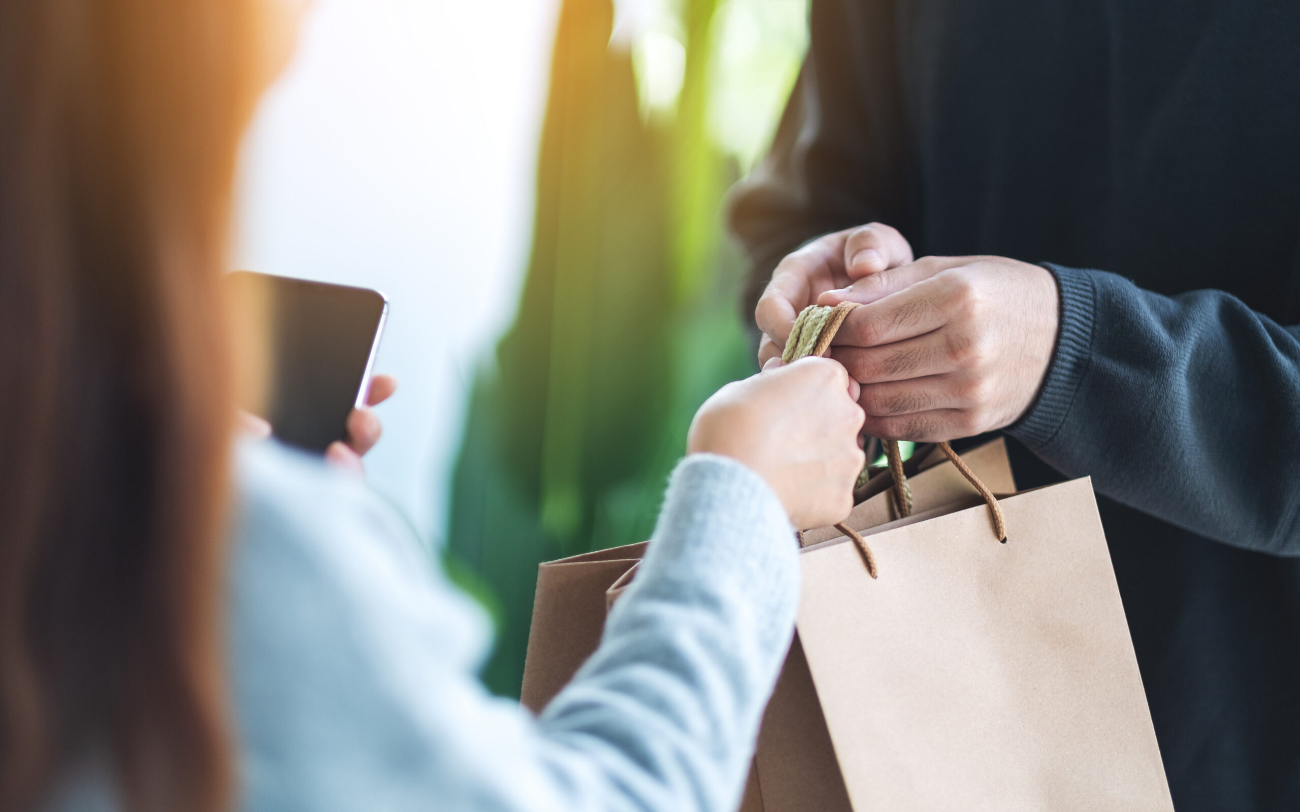 A woman receives a shopping bag, showing a clear buying signal that a purchase decision has been made.