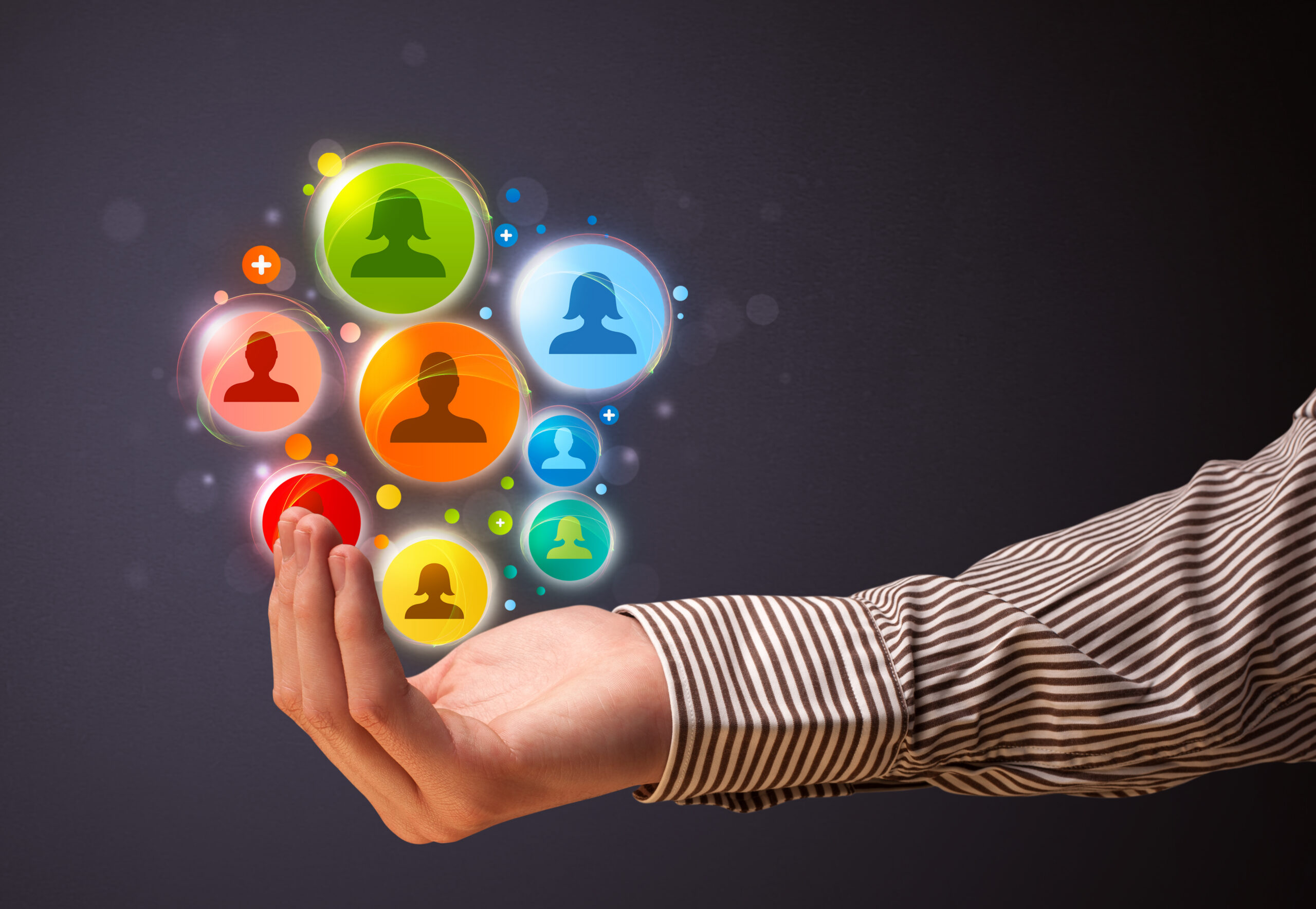 An arm holding up a set of colorful circles containing silhouettes of people, showing how to attract new customers.